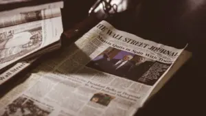 Periódico sobre una mesa de madera oscura evocando la lectura pausada de historia.