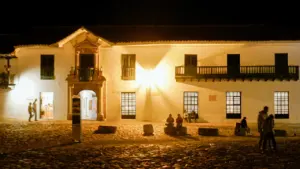 Edificio histórico iluminado de noche con personas paseando en un entorno urbano español.