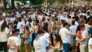 Gran multitud de jóvenes vestidos de blanco reunidos en un parque durante un festival.