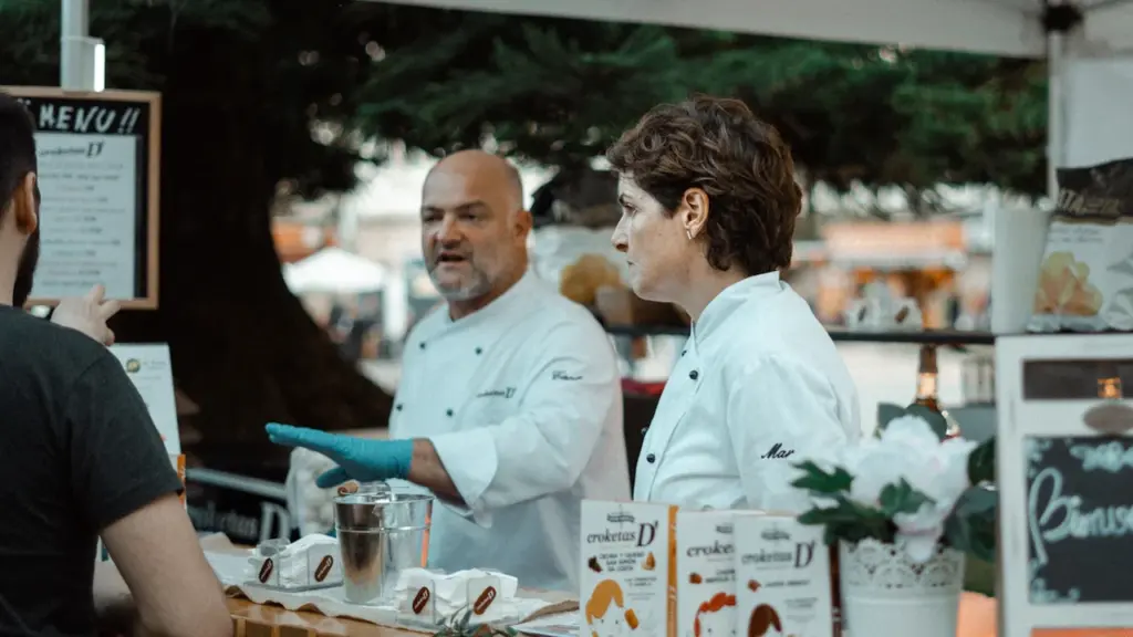 Dos chefs profesionales trabajando en su puesto de comida en un festival gastronómico.
