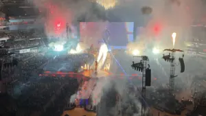 Vista panorámica de un concierto masivo con efectos pirotécnicos y luces nocturnas.