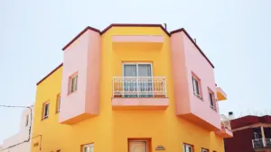 Fachada de un edificio colorido en tonos amarillos y rosas en una zona urbana.