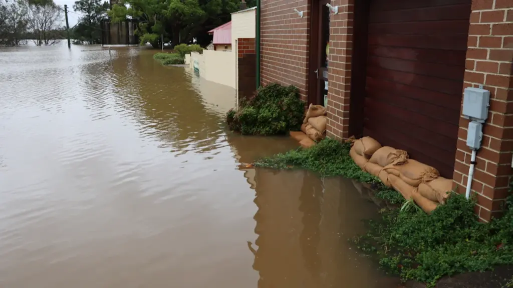 Sacos de arena protegiendo una vivienda frente a las inundaciones en una calle anegada.