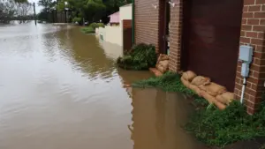 Sacos de arena protegiendo una vivienda frente a las inundaciones en una calle anegada.