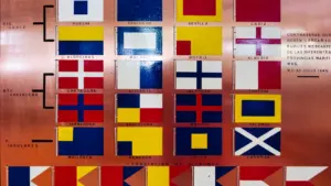 Placa histórica con banderas marítimas de diversos puertos españoles incluyendo Algeciras y Cádiz.