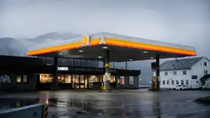 Una gasolinera bajo la lluvia con reflejos atmosféricos en el suelo húmedo.