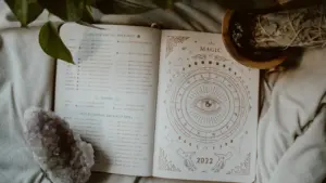 Libro de astrología abierto sobre una cama con plantas y cristales.