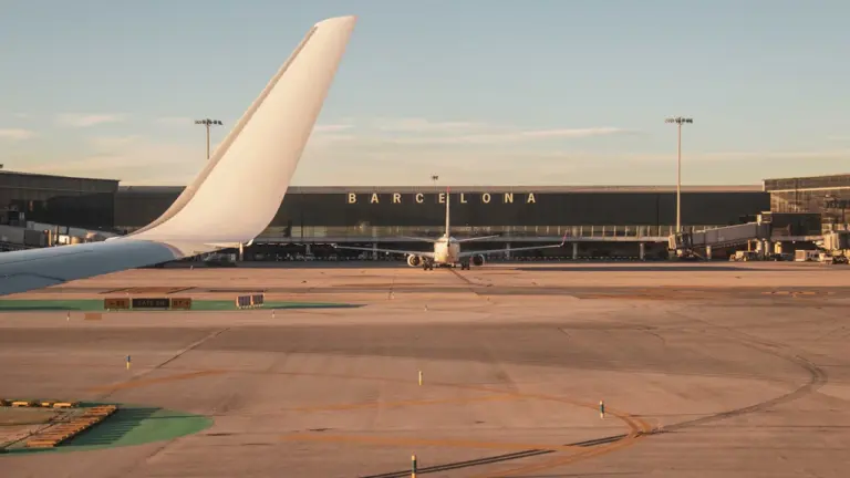 Vista del aeropuerto de Barcelona El Prat con aviones en la pista al atardecer.