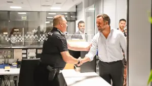 Un oficial de policía uniformado estrecha la mano de un hombre vestido con camisa formal.
