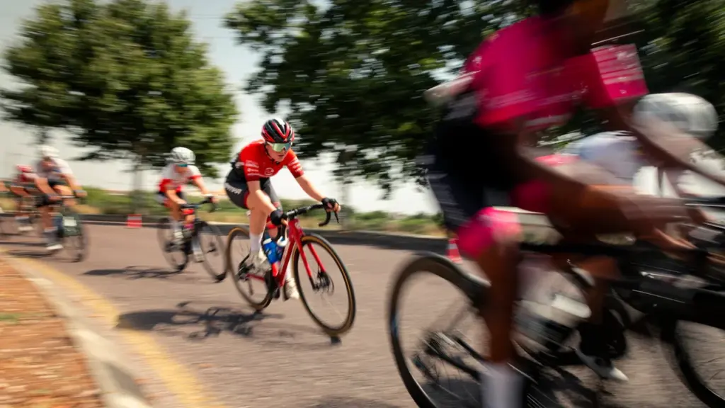 Grupo de ciclistas profesionales compitiendo en una carrera de ruta con efecto de movimiento.