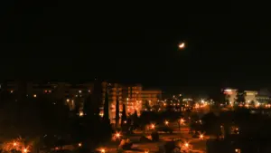 Vista panorámica nocturna de una ciudad bajo una luna creciente en el cielo