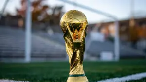 Trofeo dorado de fútbol sobre el césped frente a una portería profesional