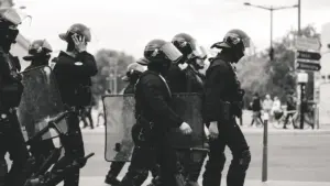 Agentes de la policía patrullando a pie por una zona urbana con equipamiento táctico.