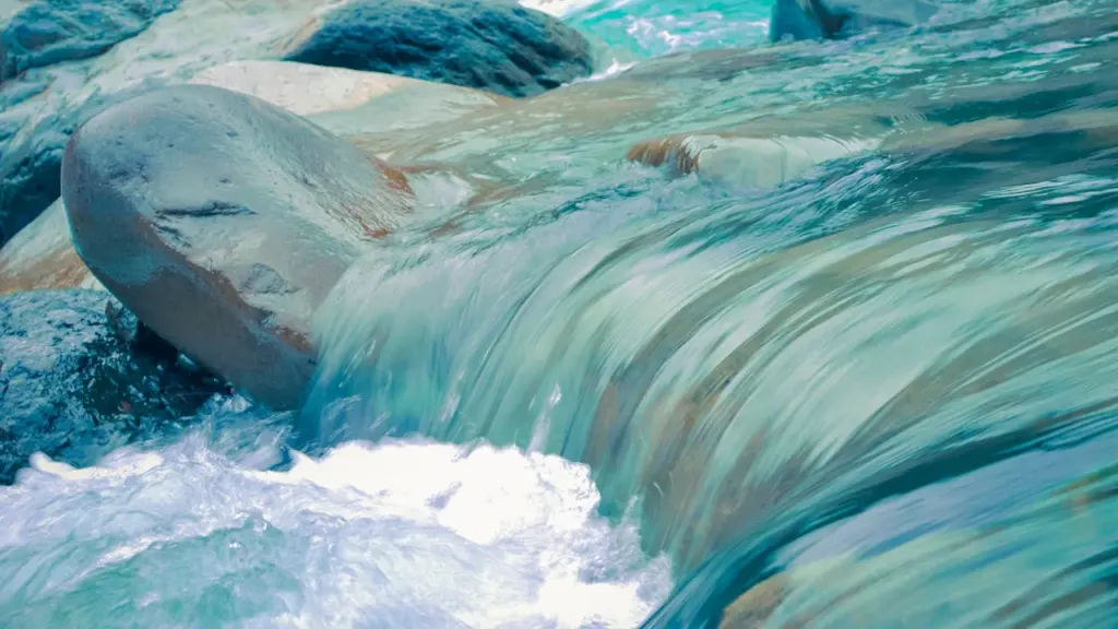 Agua turquesa cristalina fluyendo sobre rocas en un entorno natural relajante