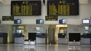 Paneles de información de salidas en un aeropuerto español con mostradores de facturación.