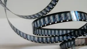 Cinta de película cinematográfica en espiral sobre un fondo blanco neutro.