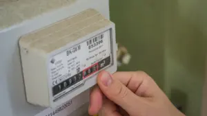 Una mano humana revisando un medidor de luz para controlar el consumo eléctrico doméstico.