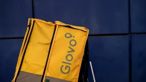 Mochila de reparto amarilla de la marca Glovo contra un fondo azul oscuro.