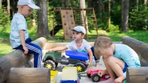 Dos niños sentados en un coche de juguete rojo en un parque infantil