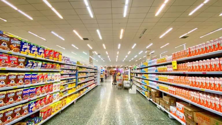 Pasillo de un supermercado con estanterías llenas de productos alimentarios y bebidas.