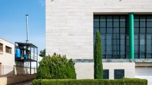 Fachada moderna de edificio industrial con amplios ventanales y estructuras metálicas en exterior.