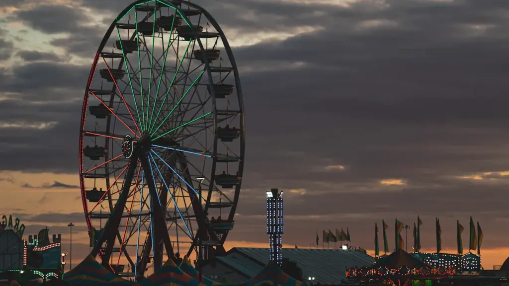 Noria iluminada al atardecer en el recinto ferial durante una noche de verano.