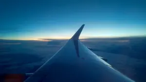 Vista desde la ventanilla de un avión sobre un manto de nubes al atardecer.