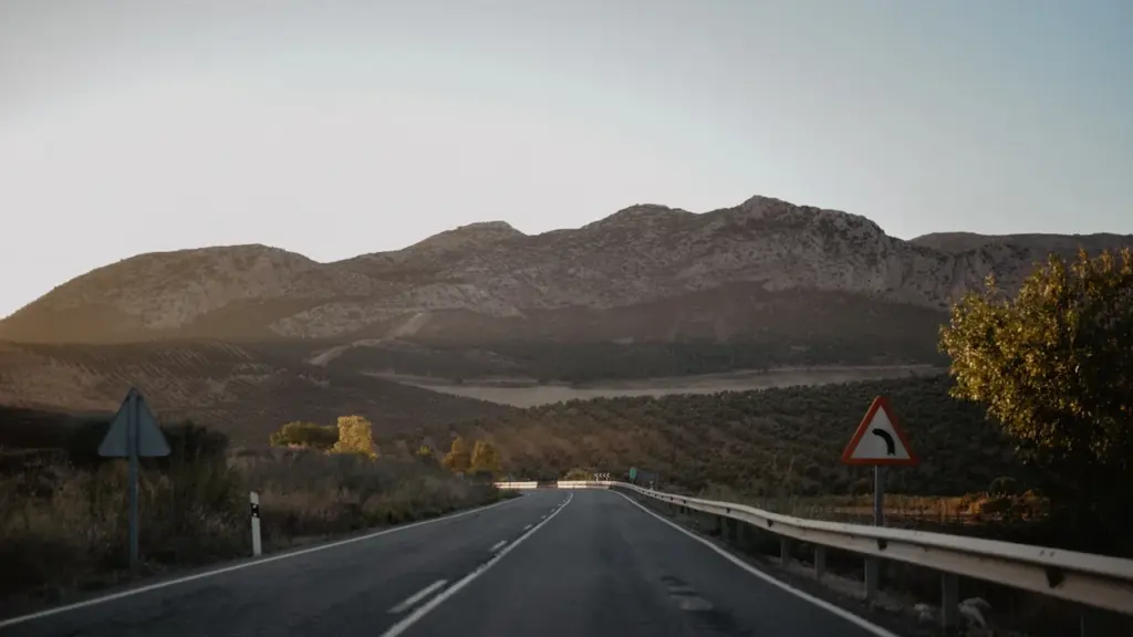 Una carretera solitaria atraviesa un paisaje árido bajo una montaña al atardecer en España.