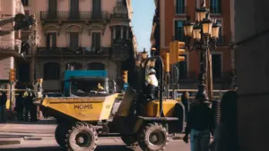 Trabajador de construcción conduce un vehículo moderno en una calle histórica de Barcelona.