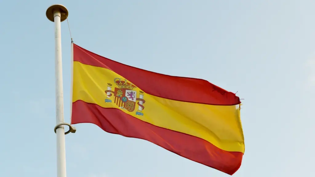 La bandera de España ondeando al viento contra un cielo despejado.